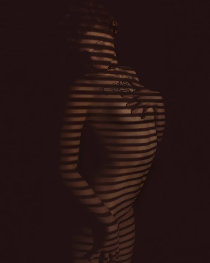Portrait by Greek photographer Nikos Latsios featuring a woman illuminated by warm window light.